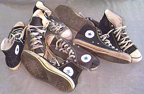 six pairs of worn black chucks on the floor