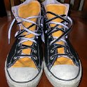 Brad Deniston Collection of Chucks  Front view of black and gold 2-tone high tops with black and white reversible shoelaces.