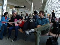 Tim Armstrong  Tim strumming his guitar in an airport waiting area.