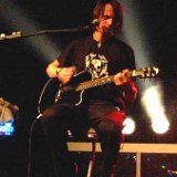 Silbermond  Guitarist Thomas Stolle seated on a stool performing in his black high top chucks.