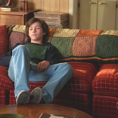 Young Sheldon  Georgie seated on the living room couch.